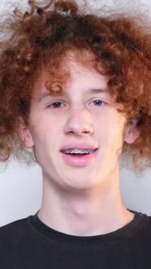 Adam stüdyodaki beyaz arka planda kameraya iyi bir jest yapıyor. Dikey video.