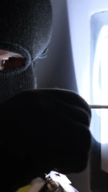 Maskeli bir soyguncu kasayı soyuyor. Bir ev soygunu. Dikey video.