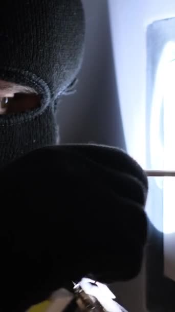 マスクに懐中電灯が入った強盗が金庫に侵入する ハウスの強盗 バーティカルビデオ — ストック動画