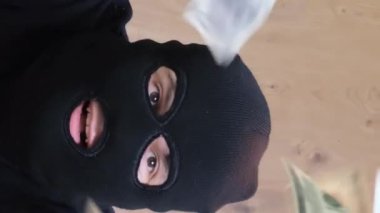 Siyah maskeli bir soyguncu kasadan para alır. Soygun tehlikesi. Dikey video.