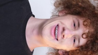Stüdyoda beyaz arka planda kameraya gülümseyen adam. Dikey video.