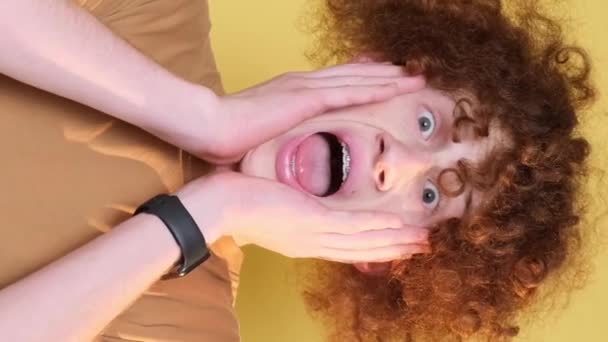 Sarı Arka Planda Şaşırmış Kıvırcık Adamın Portresi Dikey Video — Stok video