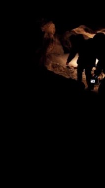 Mağara kaşifi, dalgıç, zindan, karanlık tünel, yeraltı kazısı. Ağır çekim. Dikey video.