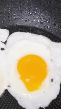 Tavada kızarmış tavuk yumurtalarının en üst görüntüsü. Kahvaltı hazırlıyorum. Dikey video.