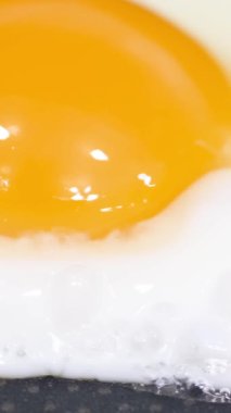 Sıcak tavada pişen bir yumurtanın yavaş çekim videosu. Dikey video.