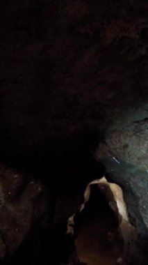 Profesyonel bir arkeolog karanlık bir mağarayı aydınlatır ve araştırır. Arkeoloji konsepti. Dikey video.