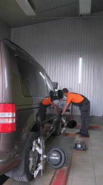 Bir araba tamircisi arabada bir Camber yapar. Araba şasisi tamiri. Araba servisi. Dikey video.