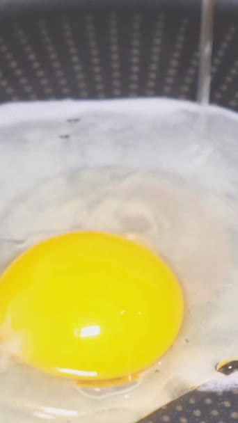 フライパンに落ちる鶏卵のクローズアップ スクランブルエッグを調理 スローモーション バーティカルビデオ — ストック動画