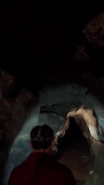 Homem Arqueólogo Com Uma Lanterna Caminha Através Uma Caverna Escura — Vídeo de Stock