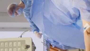 Ameliyat sırasında ameliyat masasında yaşlı bir kadın. Hasta yaşlı kadın. Ameliyat mı? Dikey video.