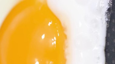 Sıcak tavada pişen bir yumurtanın yavaş çekim videosu. Dikey video.