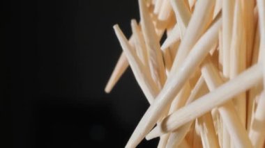 Siyah arka planda bambu kürdanları. Diş temizlemek için tahta çubuklar. Dikey video.