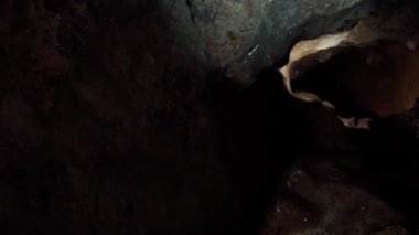 Profesyonel bir arkeolog karanlık bir mağarayı aydınlatır ve araştırır. Arkeoloji konsepti. Dikey video.