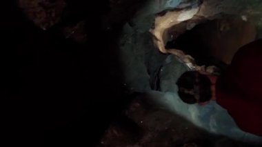 Elinde fener olan bir arkeolog karanlık bir mağarada yürüyor. Arkeoloji konsepti. Dikey video.