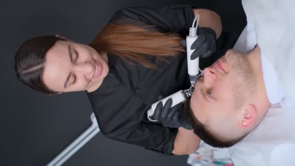 在垂直录像中 美容师正在用超声波洗掉年轻人脸上的粉刺和伤疤 垂直录像 — 图库视频影像
