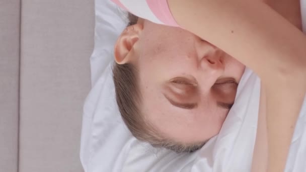 落ち込んだ病気の少女が寝室のベッドに横たわっている 人生の危機 不眠症 睡眠障害 うつ病や精神的健康問題 バーティカルビデオ — ストック動画
