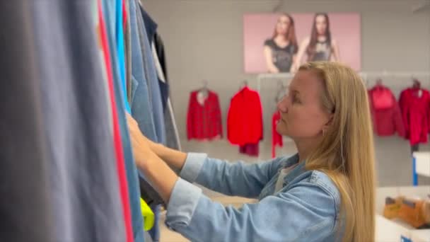 Бідна Молода Жінка Вибирає Вживаний Одяг Ощадному Магазині Жінка Оглядає — стокове відео