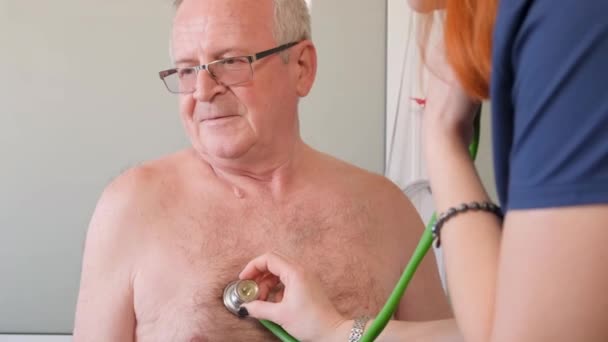 Egy Női Kardiológus Hallgat Egy Idős Ősz Hajú Nyugdíjas Mellkasára — Stock videók