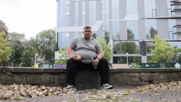 Retrato Hombre Con Sobrepeso Sentado Afuera Comiendo Bollo Bebiendo Agua — Vídeos de Stock