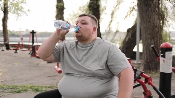 Fáradt Kövér Férfi Szürke Pólóban Vizet Iszik Egy Üvegből Miközben — Stock videók