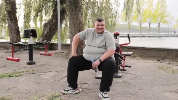 Elégedett Túlsúlyos Fiatalember Kondigépen Parkban Egy Kövér Ember Szürke Pólóban — Stock videók