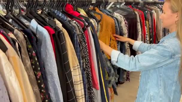 Młoda Kobieta Długimi Włosami Kupuje Używane Ubrania Biedna Kobieta Kupuje — Wideo stockowe