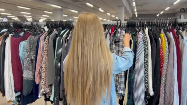 Young Poor Girl Browses Racks Clothes Thrift Store Young Woman — Stock Video