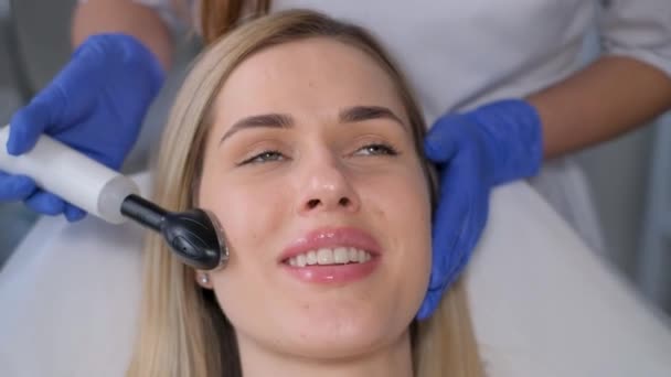 一个漂亮的女人 在美容院里 使用一位治疗师的机器接受微小电流的面部治疗 电脉冲在美容术中的应用 — 图库视频影像