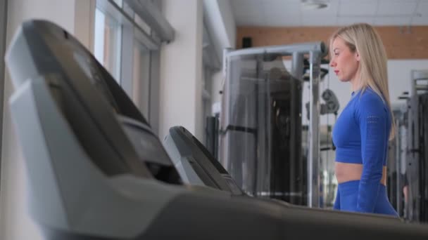 一个女人在跑步机上跑步是为了减肥和保持健康 在跑步机上跑步侧向射击 侧视图 — 图库视频影像