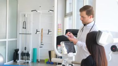 Omurilik rehabilitasyonu doktoru. Bir ortopedist bir kadını muayene eder..