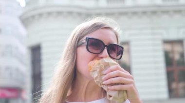 Avrupalı bir kadın yaz günü lezzetli bir kruvasan yiyor. Lezzetli hamur işleri. Fransa 'ya Turizm