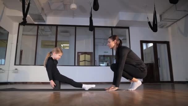 Een Vrouwelijke Trainer Een Meisjesturnster Hal Tijdens Een Repetitie Stretching — Stockvideo