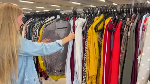 Μια Γυναίκα Μακριά Μαλλιά Αγοράζει Μεταχειρισμένα Ρούχα Ένα Κατάστημα Ρούχων — Αρχείο Βίντεο