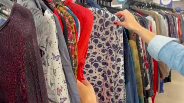 ハンガーに使用された服を選択する女性の手のクローズアップ セカンドハンド 貧困について — ストック動画