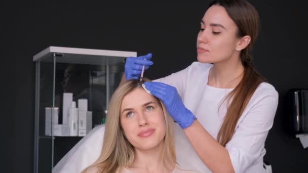化粧品学者は ボツリヌス毒素を 女の子の頭に注射し 閉じ込めます 化粧品クリニックでのヘアメセラピー手順 髪の成長のためのメソセラピー 女性は頭に注射を受けます — ストック動画