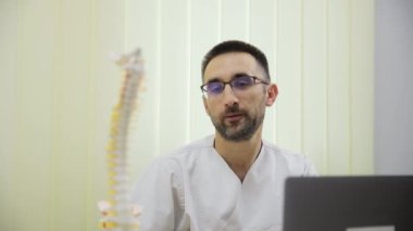 Omurganın anatomik modelini gösteren bir ortopedi doktorunun portresi. Modern tıp.