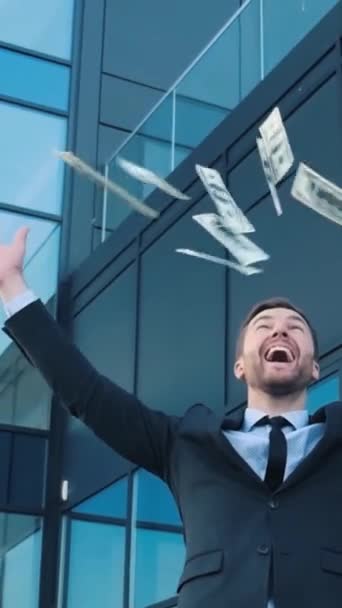 一个穿正装 打着领带的男人把钱抛向空中 在一座玻璃建筑外面摆出一副气派的样子 — 图库视频影像