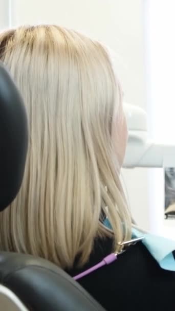 Μια Γυναίκα Ξανθά Μαλλιά Και Αφέλειες Κάθεται Μια Οδοντιατρική Καρέκλα — Αρχείο Βίντεο