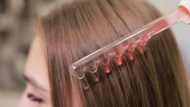 女性はマゼンタ色で彼女の自然な髪を強化する木製のファッションアクセサリーを使用して髪の治療を受けています — ストック動画