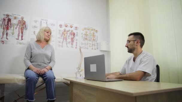 Uma Mulher Idosa Uma Consulta Médica Ortopédica Com Modelo Anatomia — Vídeo de Stock
