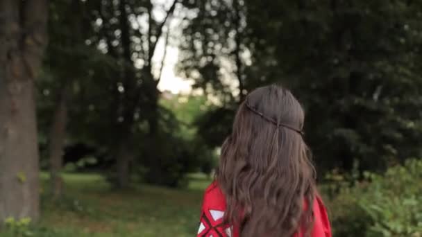 幸せな女性 赤いコートを着て 穏やかな森の風景の中で木々や植物の間に散歩 — ストック動画