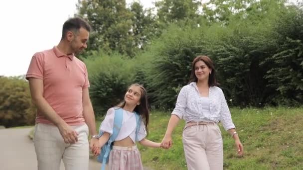 一个快乐的家庭正在公园里散步 享受悠闲的散步 牵着手和微笑 茂盛的绿草 树木和植物增添了欢乐的气氛 — 图库视频影像