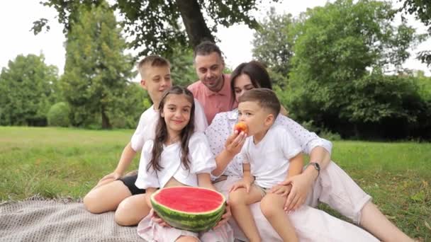 Família Feliz Compartilha Piquenique Parque Comendo Melancia Enquanto Sorri Desfruta — Vídeo de Stock
