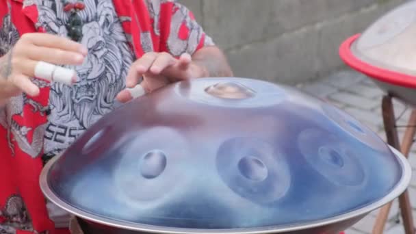这个人在悬挂的鼓上创作音乐 用双手发出流畅而有节奏的声音 如炊具中的水 将煤气灯和蓝色的电艺术结合在一起 形成一个迷人的娱乐圈 — 图库视频影像