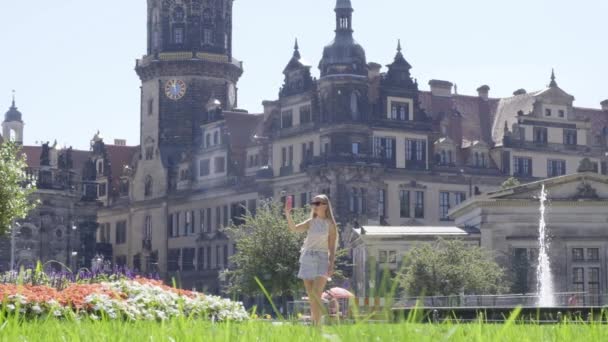 女性は緑豊かな草や植物に囲まれた中世の城を賞賛する公園にあり 都市景観の都市デザインを強化します — ストック動画