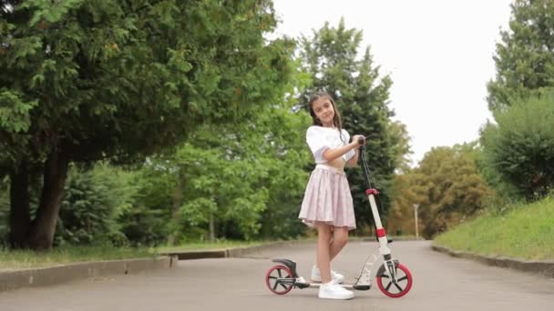 Ένα Μικρό Κορίτσι Είναι Χαρούμενα Γλιστρώντας Στο Σκούτερ Της Τους — Αρχείο Βίντεο