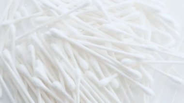 Sanatsal bir görüntüye benzeyen ahşap döşeme desenli bej bir yüzeye yerleştirilmiş beyaz pamuklu çubuklar yığını..