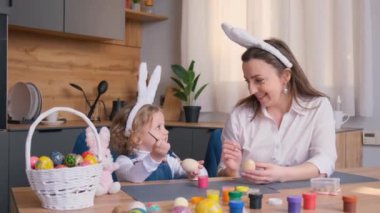 Bir kadın ve küçük bir kız paskalya yumurtalarını tezgaha boyamak için sofra takımı kullanıyorlar..