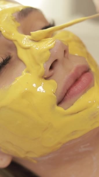 Cosmetólogo Aplica Máscara Alginato Oro Amarillo Con Espátula Cara Una — Vídeo de stock