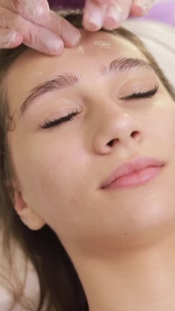 用美容师的按摩动作在女性面部涂上一层乳膏 并采用羧疗法 美眉有化妆品按摩 面部处理 垂直录像 — 图库视频影像